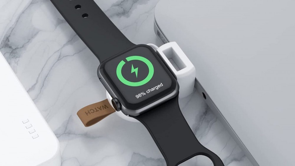 Compact white Apple Watch charger charging an Apple Watch while plugged into a MacBook USB port