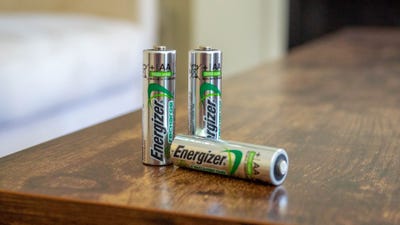 Three rechargable AA Energizer batteries standing on a wood table